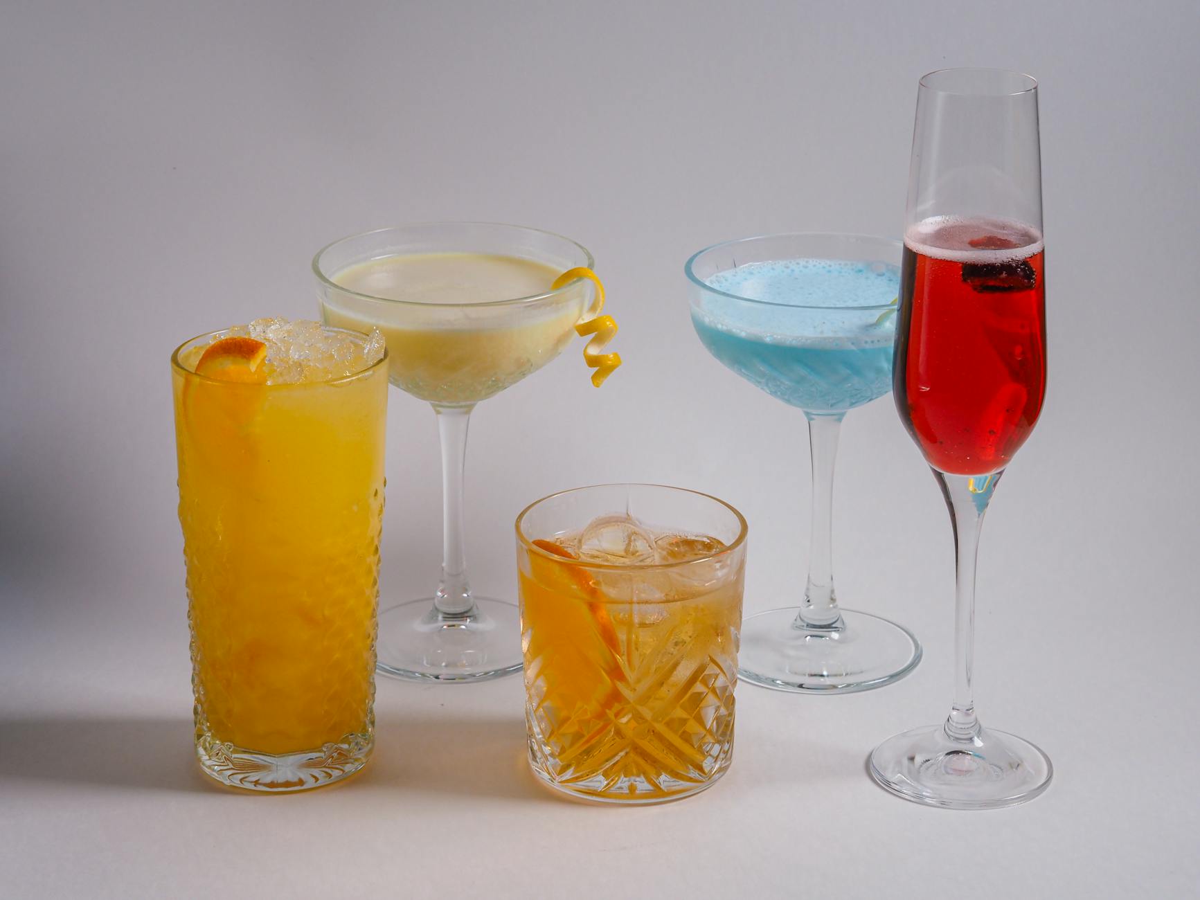 Różnokolorowe drinki w różnych szklankach na białym tle