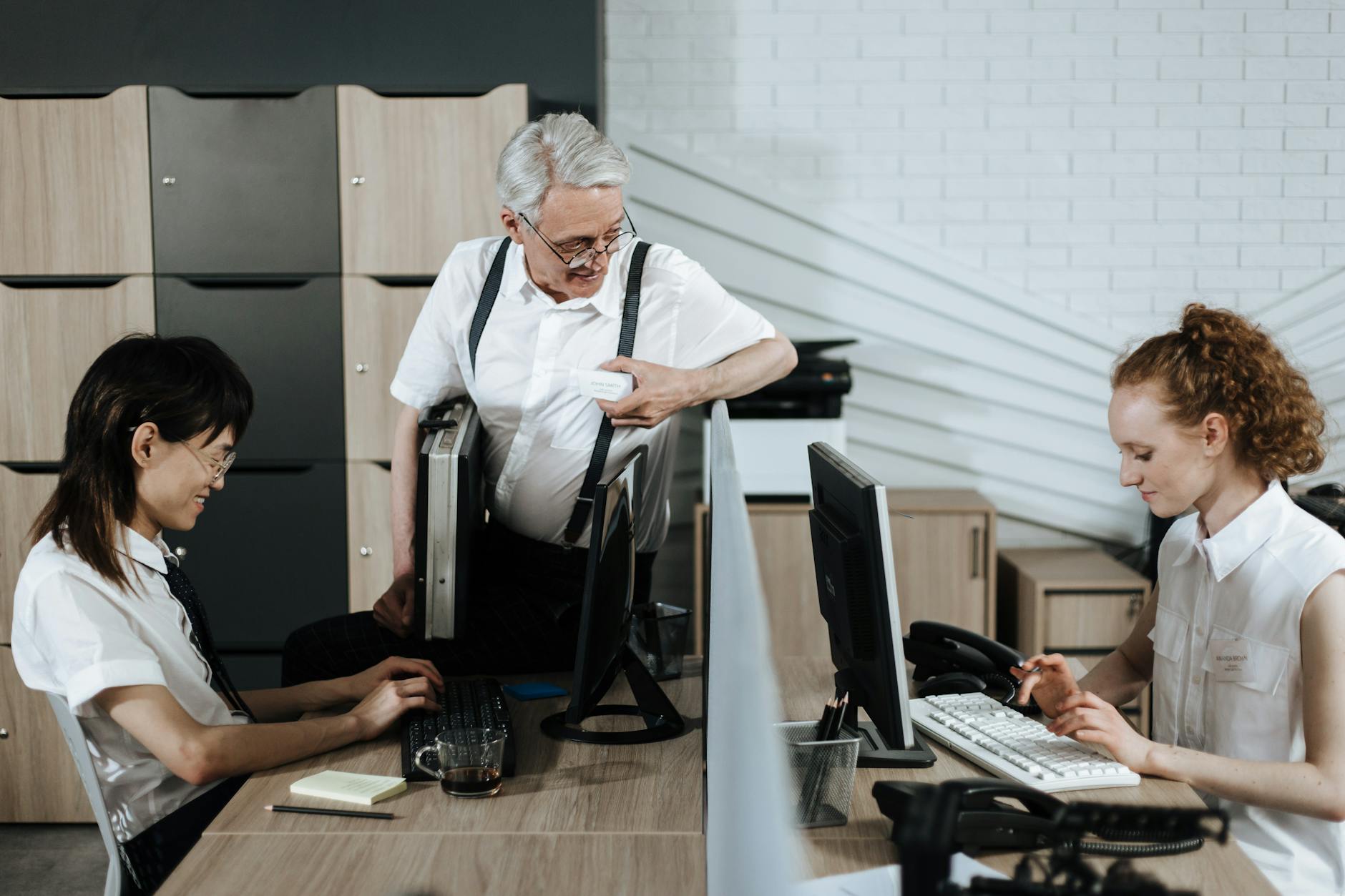 Zespół biurowy przy biurkach omawia zadania z użyciem laptopów