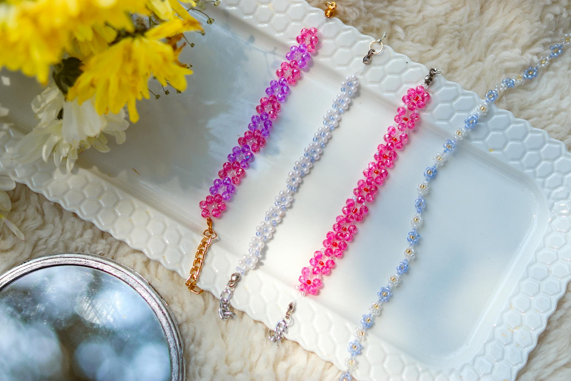 Kolorowe bransoletki z koralików z hematytu na białej tacy z kwiatami