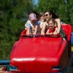 Rodziny z dziećmi jadą kolejką górską w parku rozrywki