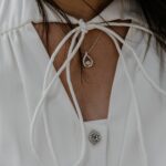 Kobieta w białej bluzce z delikatnym naszyjnikiem z diamentową zawieszką