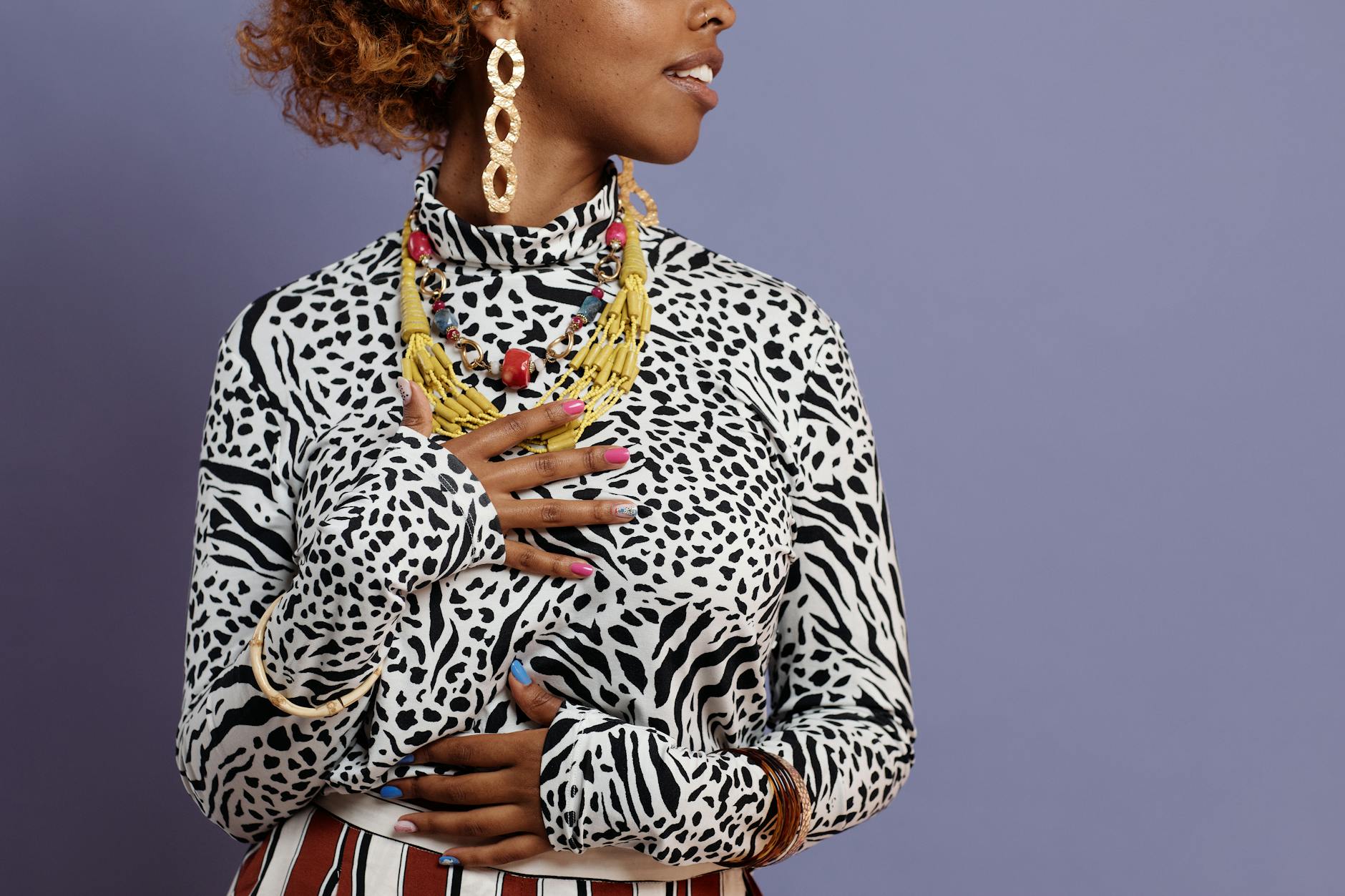 Kobieta w biżuterii i ubraniu w panterkę na fioletowym tle