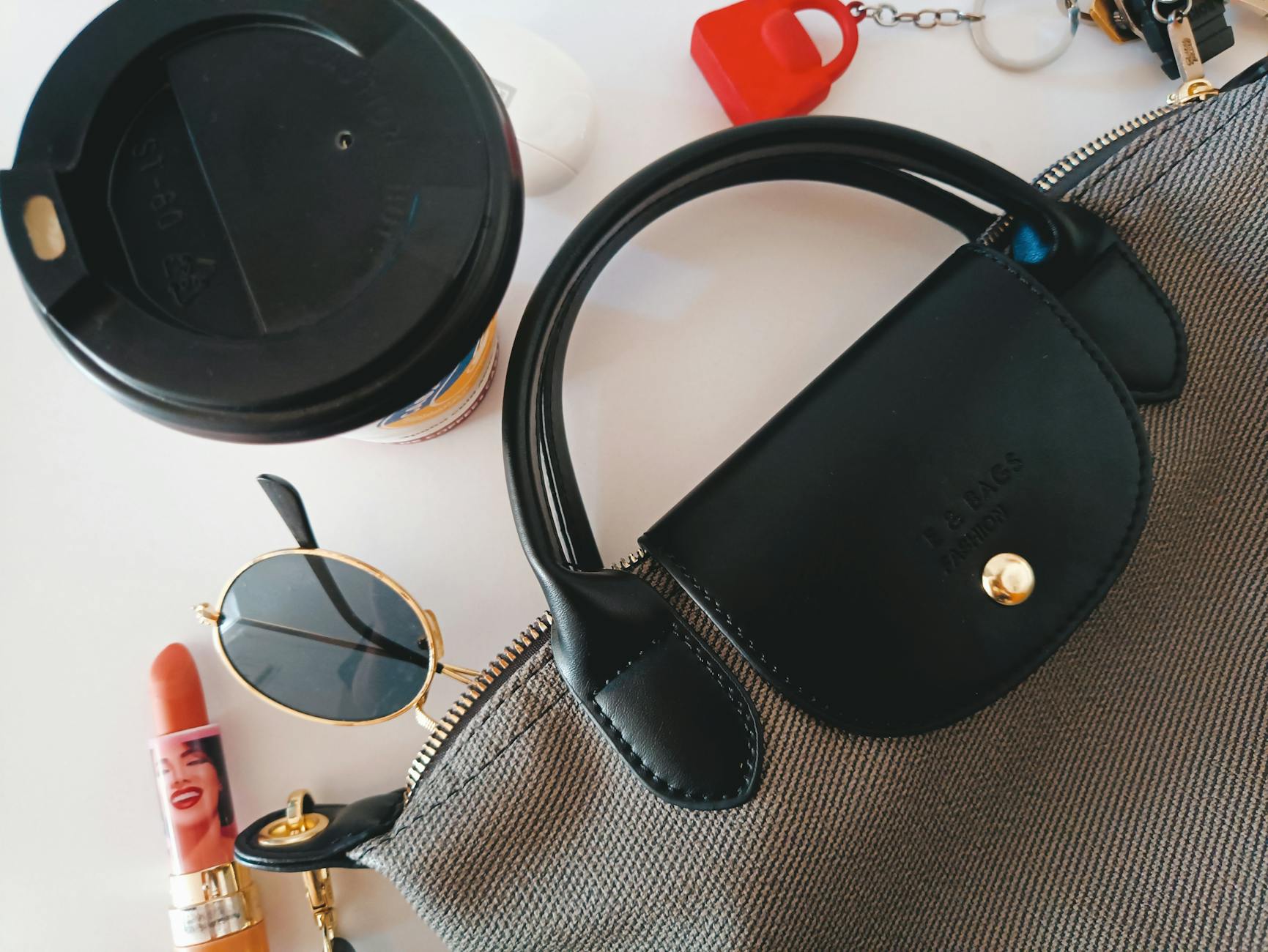 Płaskie ujęcie torebki z zawieszką, okularów, szminki i filiżanki kawy