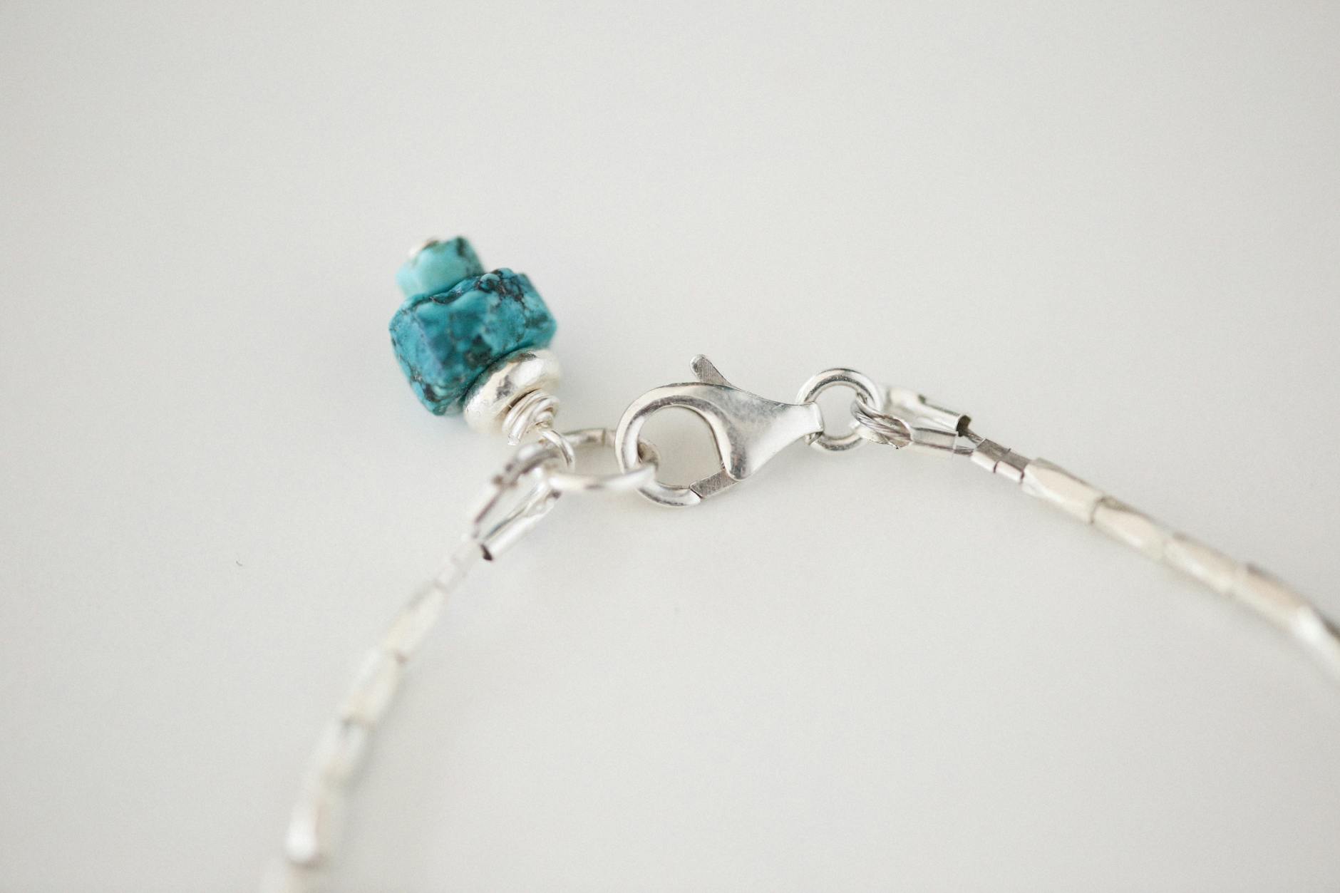 Srebrna bransoletka z turkusowym kryształem na białym tle