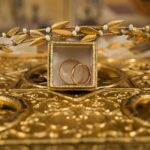 Złote obrączki i delikatna tiara na ozdobnym złotym tle